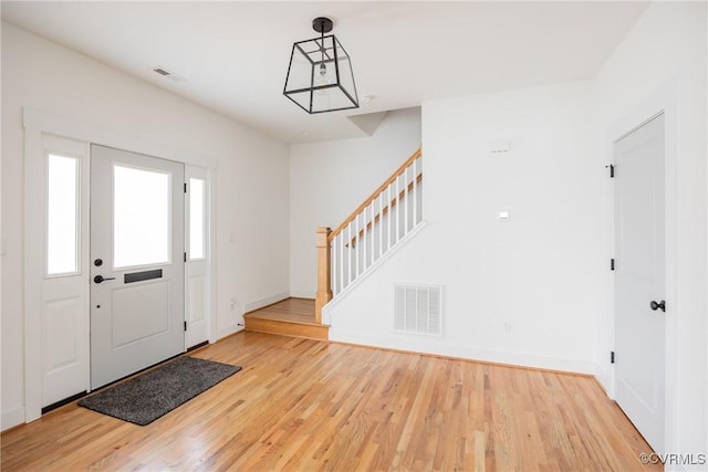 foyer featuring stairway, baseboards, visible vents, and wood finished floors