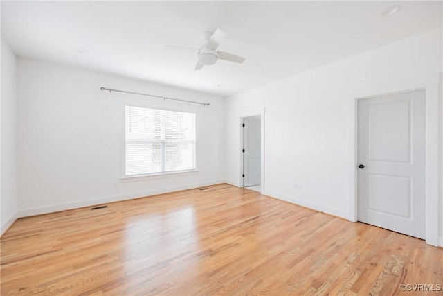 unfurnished room with ceiling fan, light wood finished floors, visible vents, and baseboards