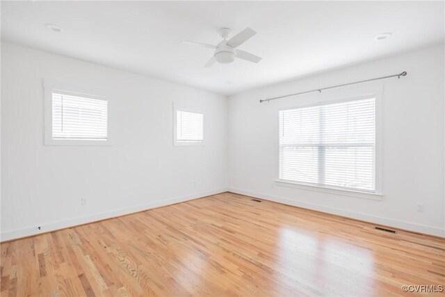 unfurnished room featuring light wood-type flooring, visible vents, and a healthy amount of sunlight