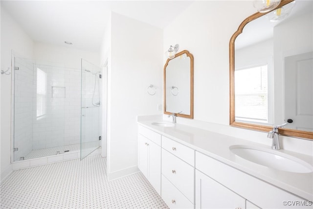 bathroom with double vanity, a shower stall, baseboards, and a sink