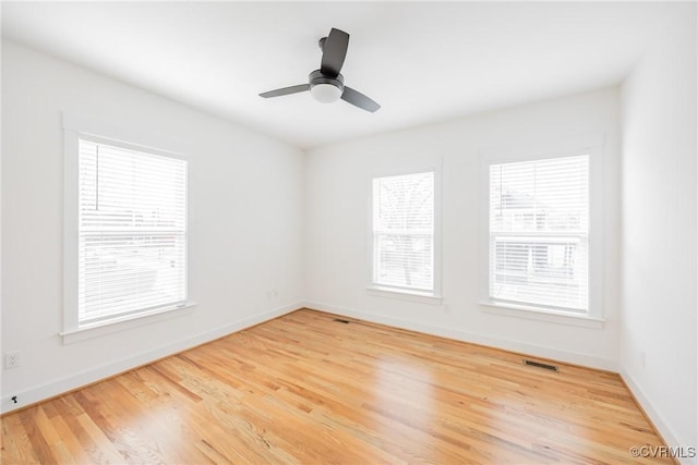 spare room featuring baseboards, visible vents, ceiling fan, and wood finished floors