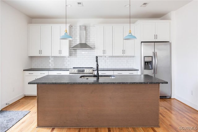 kitchen featuring visible vents, appliances with stainless steel finishes, a sink, wall chimney range hood, and an island with sink