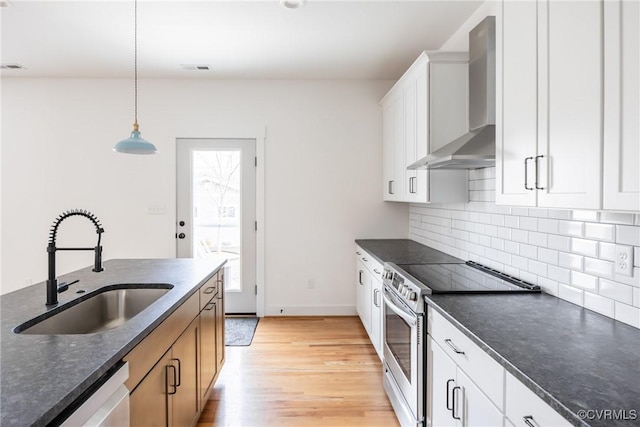 kitchen with plenty of natural light, dishwasher, stainless steel range with electric cooktop, wall chimney range hood, and a sink