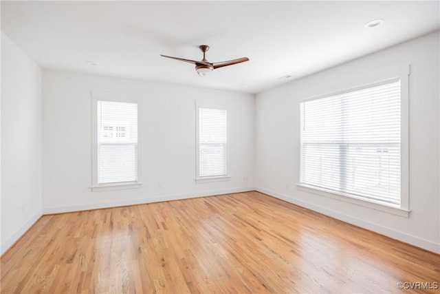 spare room with baseboards, ceiling fan, and light wood-style floors