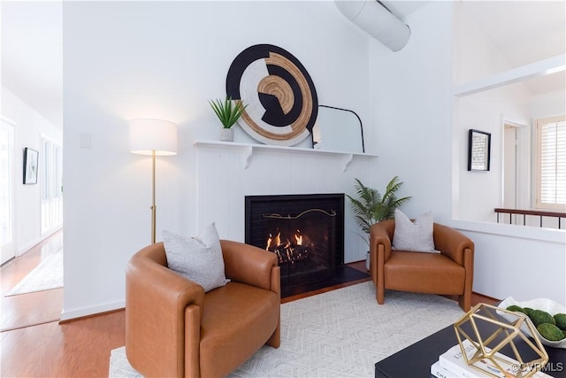 sitting room with a fireplace with flush hearth, baseboards, and light wood finished floors