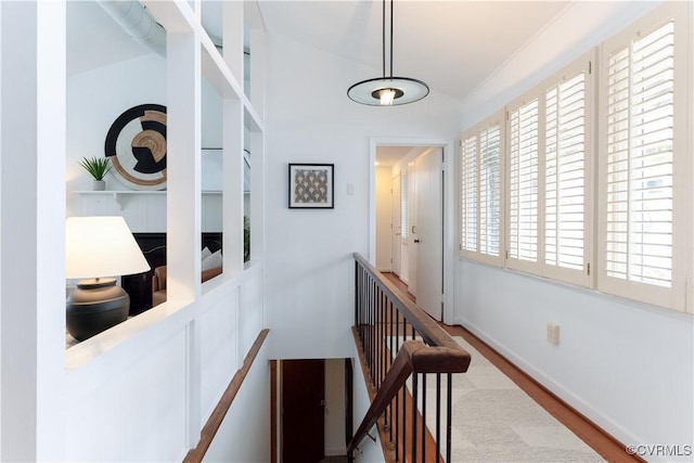 hall with wood finished floors, an upstairs landing, and baseboards