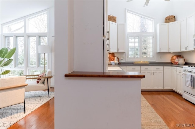 kitchen featuring dark countertops, white appliances, light wood-style flooring, and white cabinets