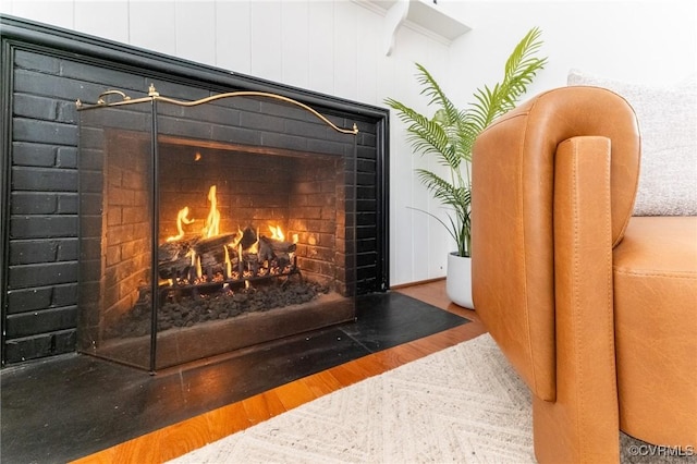 details with a warm lit fireplace and wood finished floors