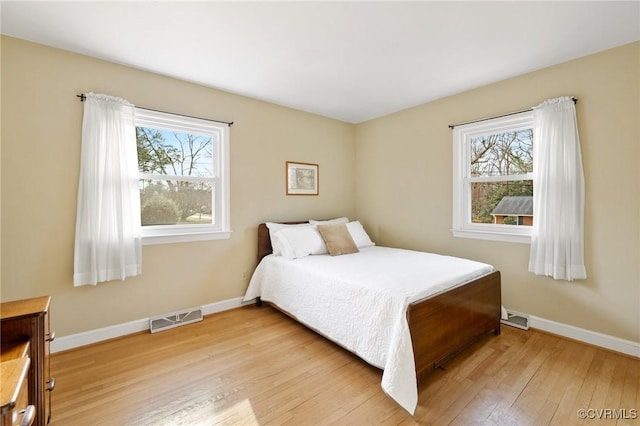 bedroom featuring light wood-style flooring, visible vents, and baseboards