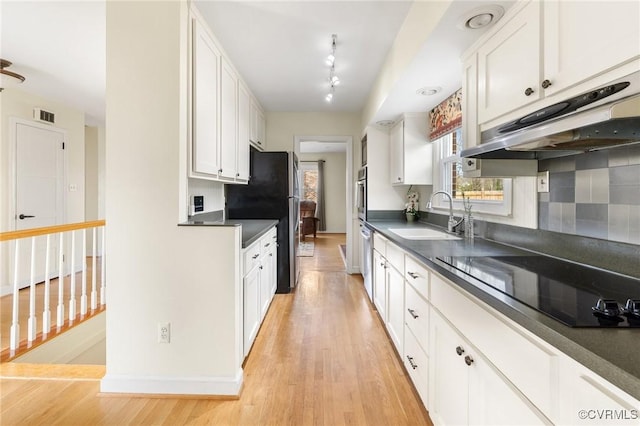 kitchen featuring visible vents, dark countertops, black electric cooktop, white cabinetry, and a sink