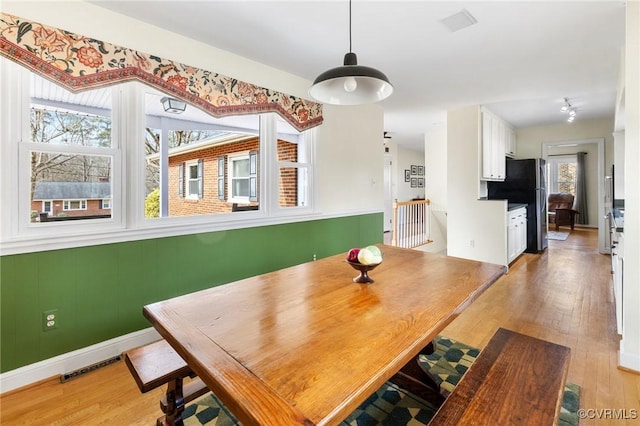 dining room featuring light wood finished floors, visible vents, and baseboards