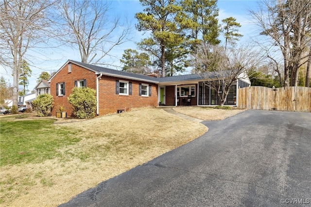 ranch-style home featuring driveway, a front yard, fence, and brick siding