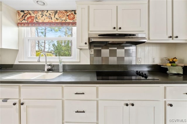 kitchen with dark countertops, black electric stovetop, white cabinetry, and a sink