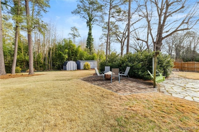 view of yard with an outbuilding, a shed, a patio area, and fence