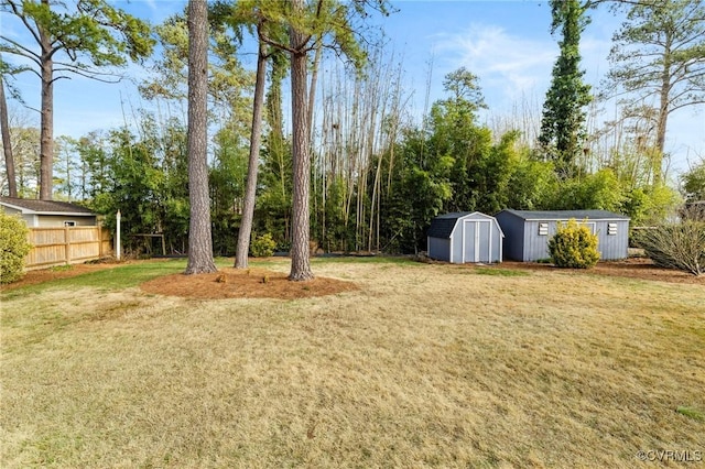 view of yard featuring a shed, an outdoor structure, and fence