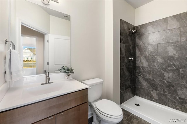 full bath with toilet, a tile shower, and vanity