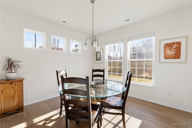 dining room with baseboards, visible vents, and wood finished floors