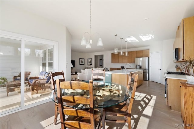 dining area with light wood-type flooring and a notable chandelier