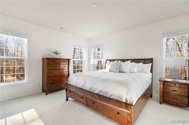 bedroom with light colored carpet, visible vents, baseboards, and multiple windows