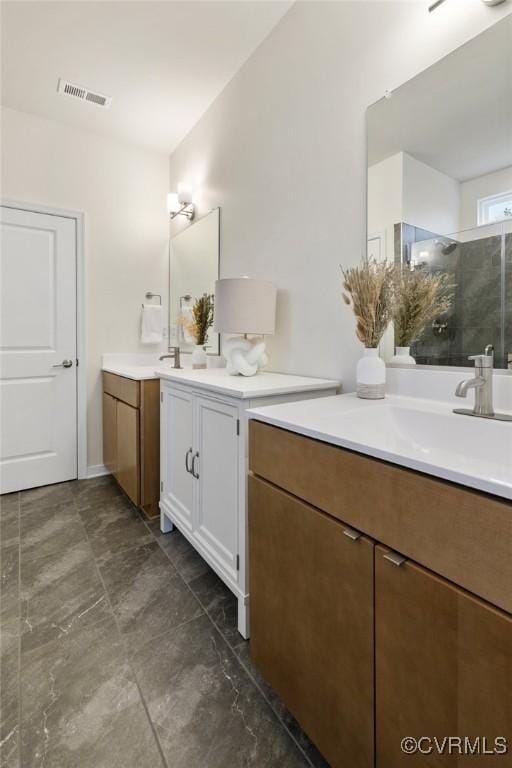 bathroom featuring a stall shower, visible vents, two vanities, and a sink