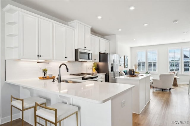 kitchen featuring stainless steel appliances, white cabinetry, sink, and kitchen peninsula