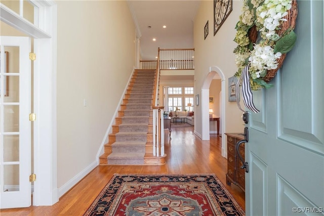 foyer with arched walkways, baseboards, light wood finished floors, and recessed lighting