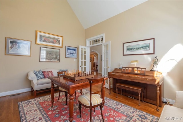 interior space with high vaulted ceiling, wood finished floors, visible vents, baseboards, and french doors