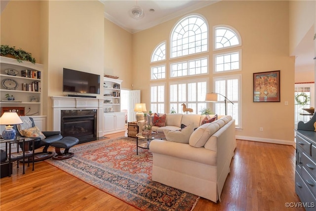 living room with a wealth of natural light, a premium fireplace, ornamental molding, and wood finished floors