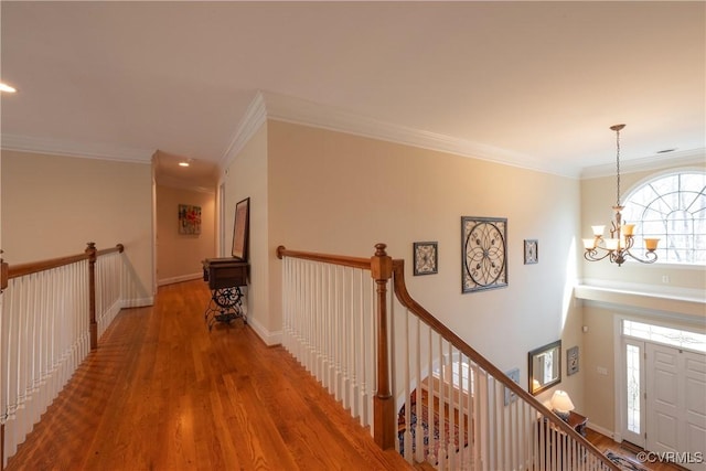 hallway with crown molding, an upstairs landing, wood finished floors, a chandelier, and baseboards