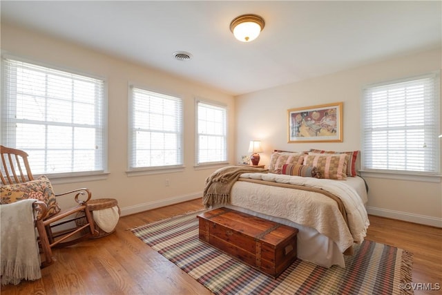 bedroom with multiple windows, light wood-type flooring, and visible vents