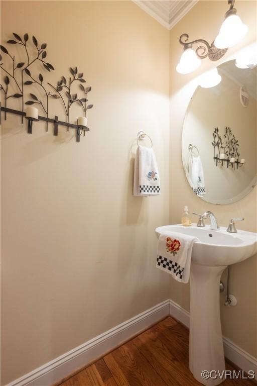 bathroom with crown molding, wood finished floors, and baseboards