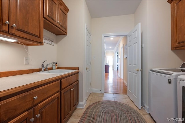 clothes washing area with washer and clothes dryer, light tile patterned floors, cabinet space, a sink, and baseboards