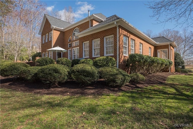 view of side of property with a lawn and brick siding