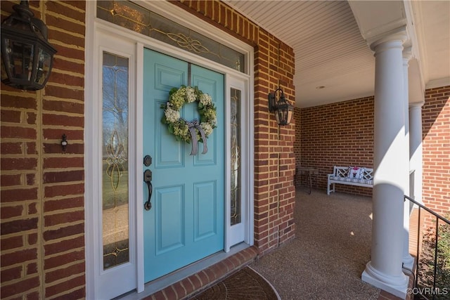 view of exterior entry with covered porch and brick siding