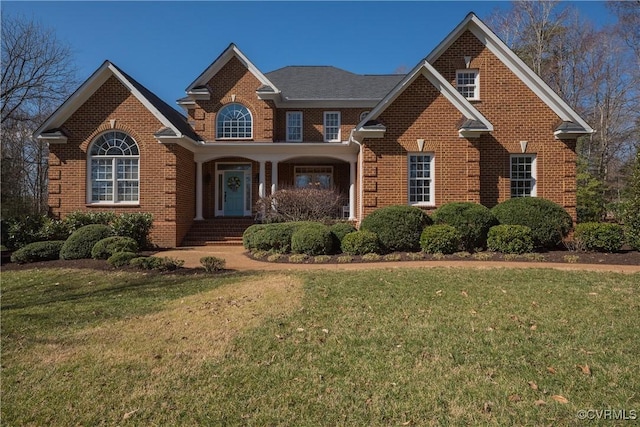 traditional home featuring a front yard and brick siding