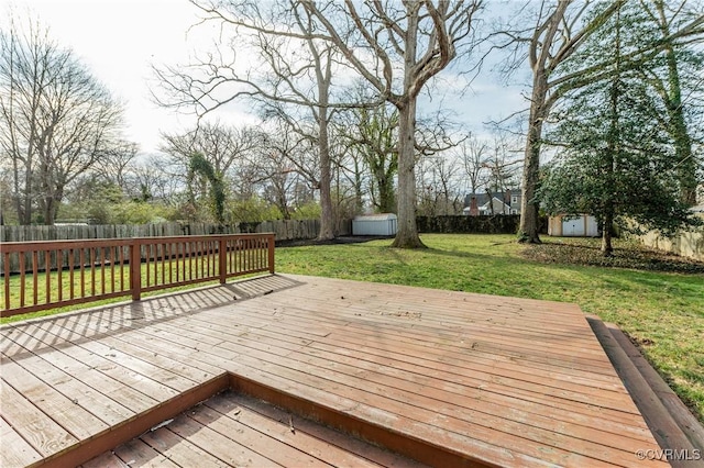 wooden deck featuring a yard, a fenced backyard, an outdoor structure, and a storage unit