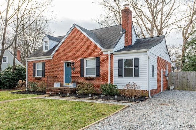 view of front of home with a front yard, brick siding, fence, and a chimney