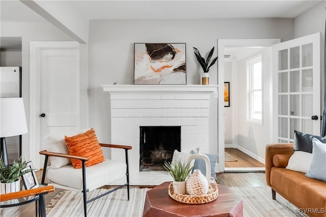 sitting room with a fireplace, wood finished floors, and baseboards