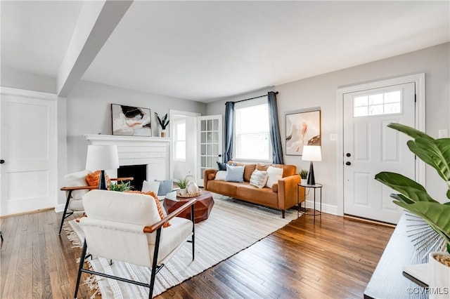 living area featuring a fireplace, baseboards, and wood finished floors