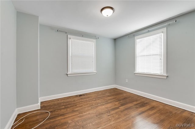 spare room with baseboards and wood finished floors