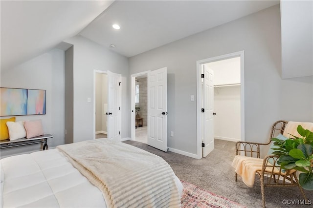 bedroom with recessed lighting, light carpet, baseboards, vaulted ceiling, and a walk in closet