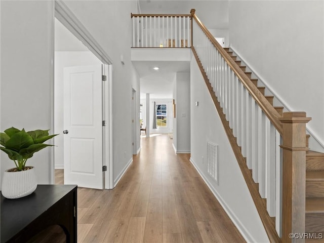 interior space featuring a towering ceiling and light hardwood / wood-style flooring