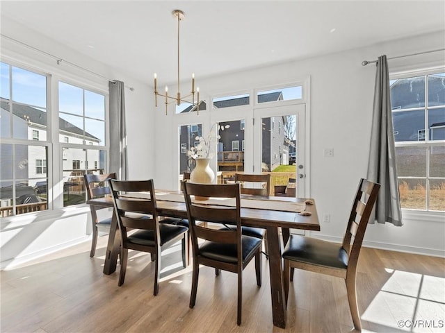 dining room with a notable chandelier, baseboards, and wood finished floors