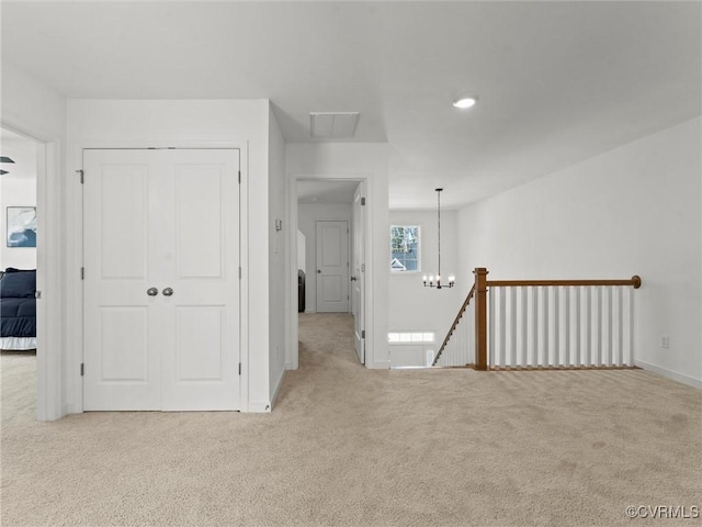 empty room with light carpet, baseboards, and a notable chandelier