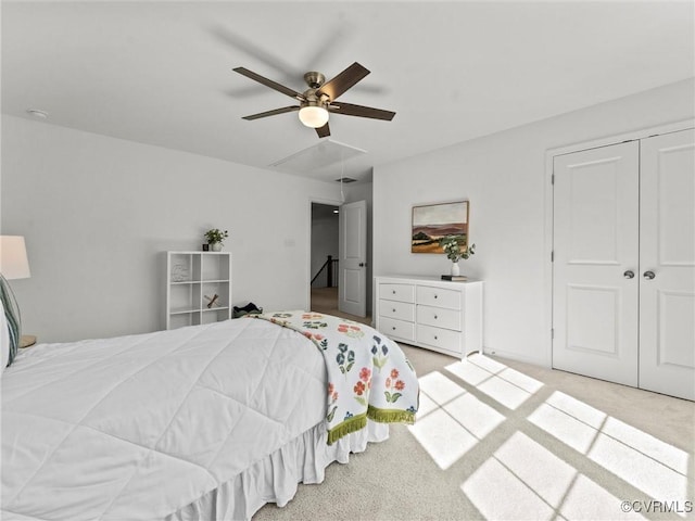 bedroom with ceiling fan, a closet, attic access, and light colored carpet