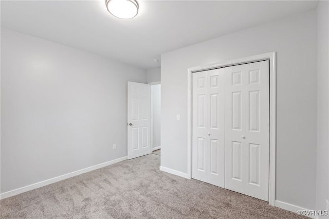 unfurnished bedroom featuring light colored carpet and a closet