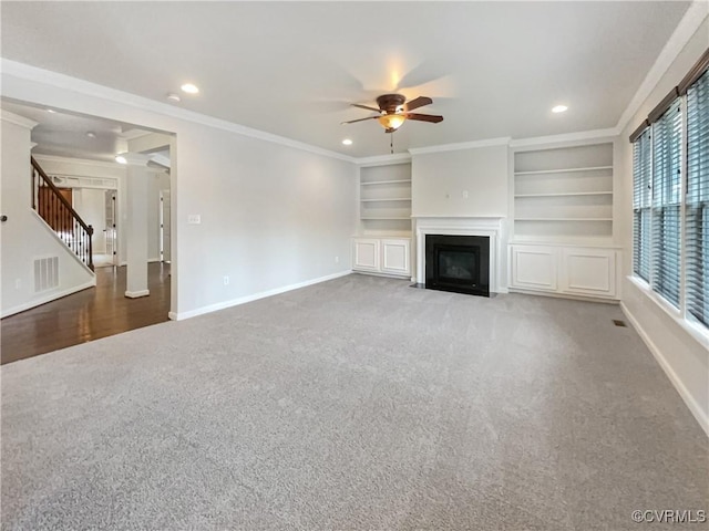 unfurnished living room with crown molding, carpet, ceiling fan, and built in shelves