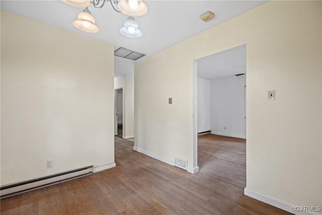 spare room with wood-type flooring and a baseboard heating unit