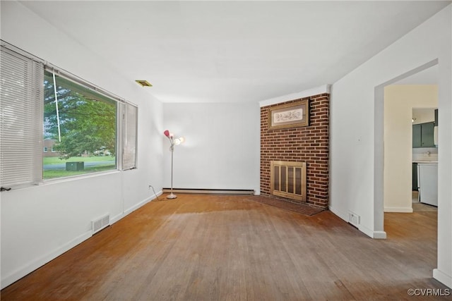 unfurnished living room featuring a brick fireplace, a baseboard radiator, and light hardwood / wood-style floors