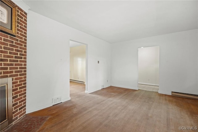 unfurnished living room with hardwood / wood-style flooring, a brick fireplace, and baseboard heating